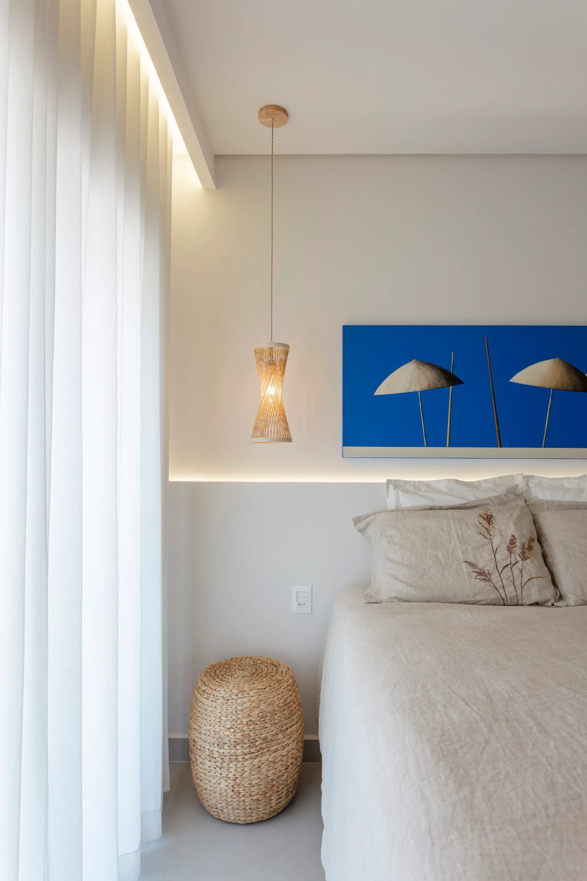 Quarto claro com cabeceira baixa iluminada por LED, quadro azul e pendente de fibra natural