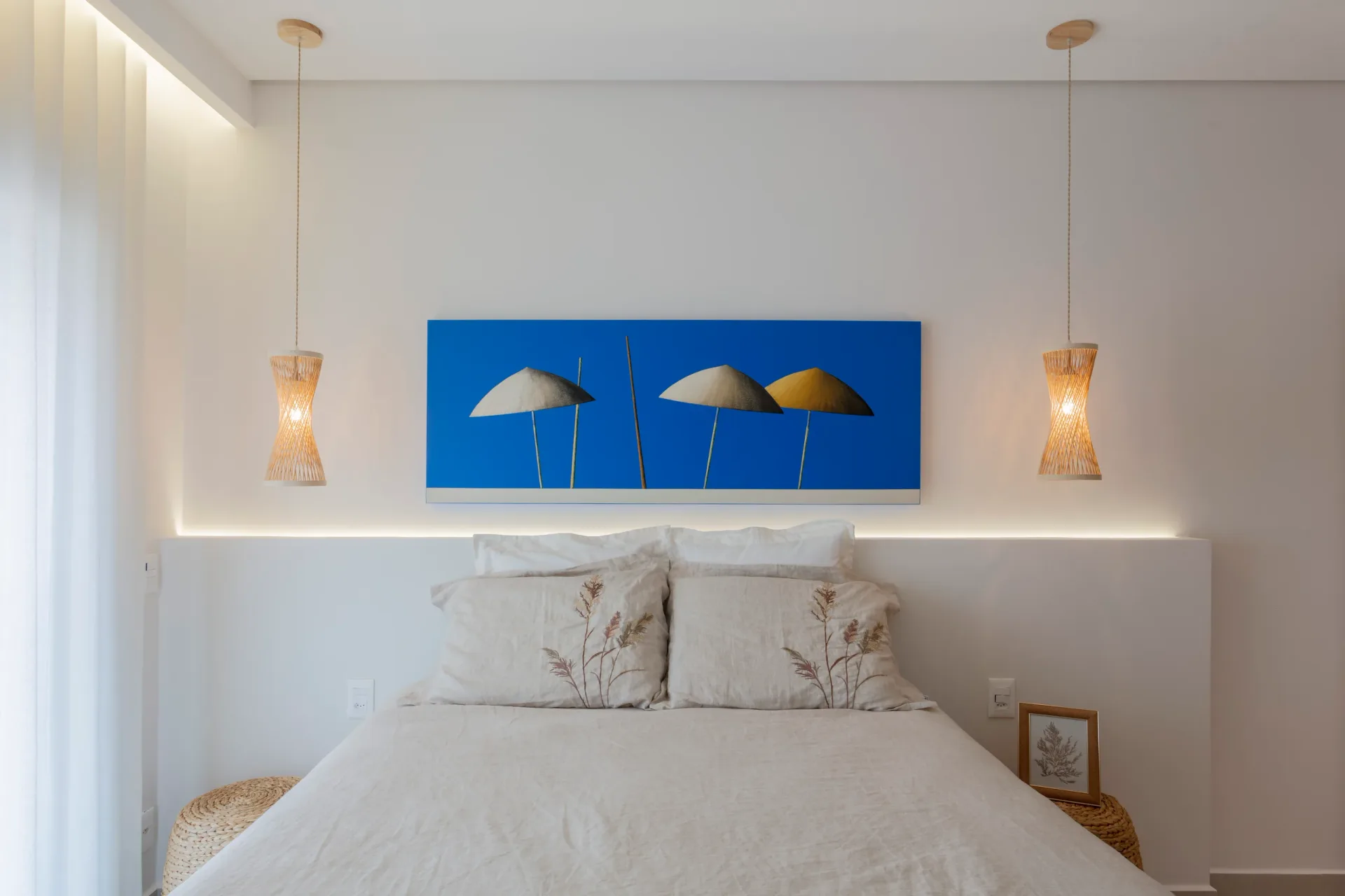Quarto claro visto de lado, com pendentes de fibra natural, quadro azul e cesto de palha